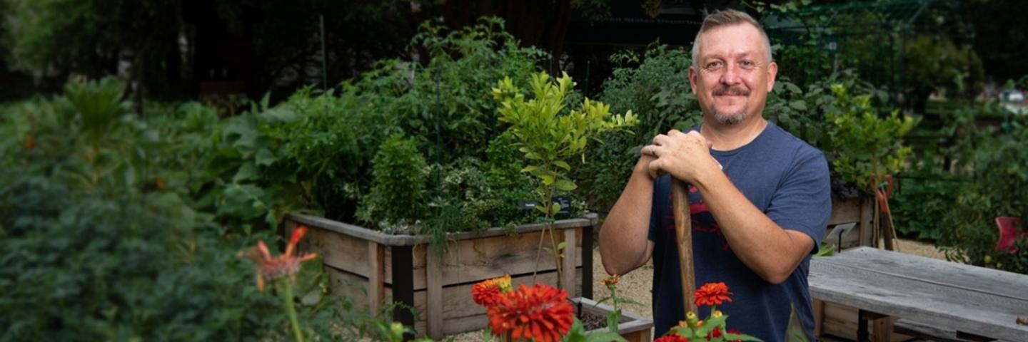 A volunteer stands in a garden