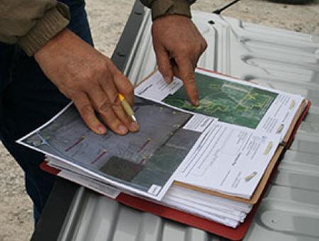Hands pointing at a conservation plan document and map.