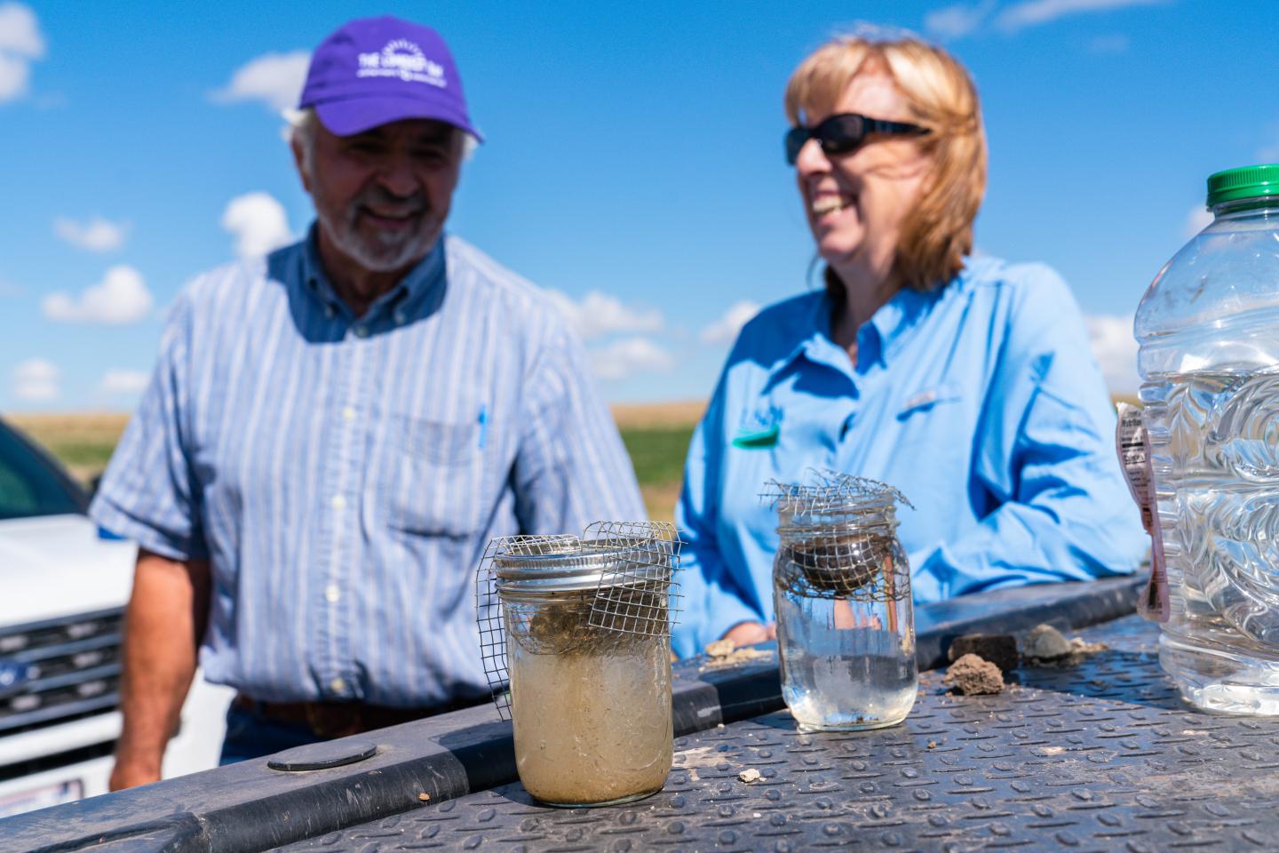 Producer Dan Buerkle and NRCS Supervisory District Conservationist Ann Fischer conduct soil aggregrate test. Soil sample on right is from no-till diverse crop field; sample on left is from tilled, field edge. B&B Farms, Fallon County, MT.