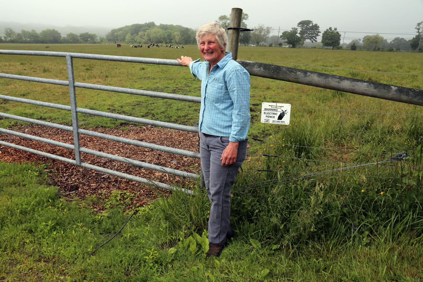 Farmer Martha Neal standing by a fence in a field.