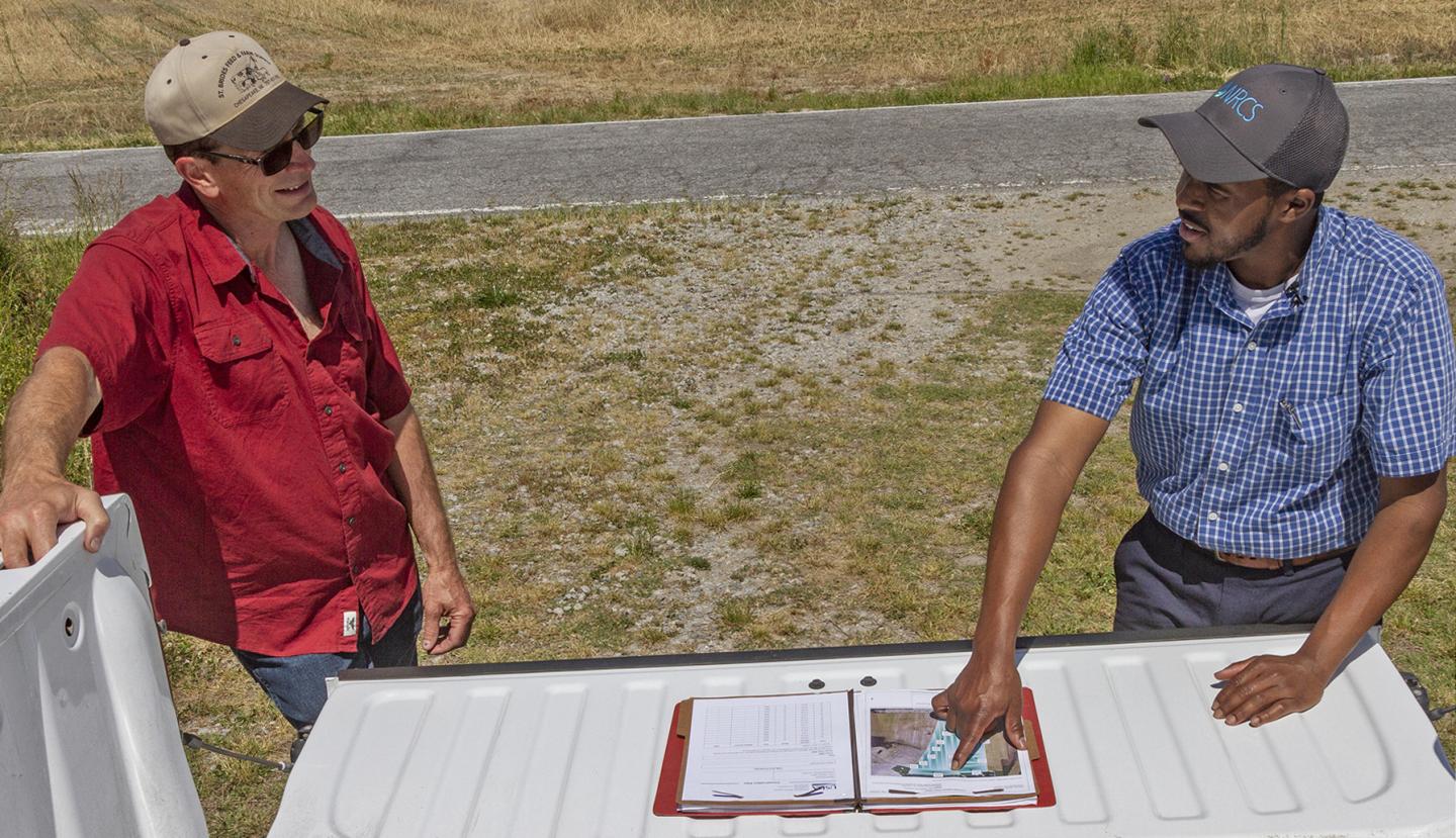 District Conservationist reviewing a plan with a landowner in the field.