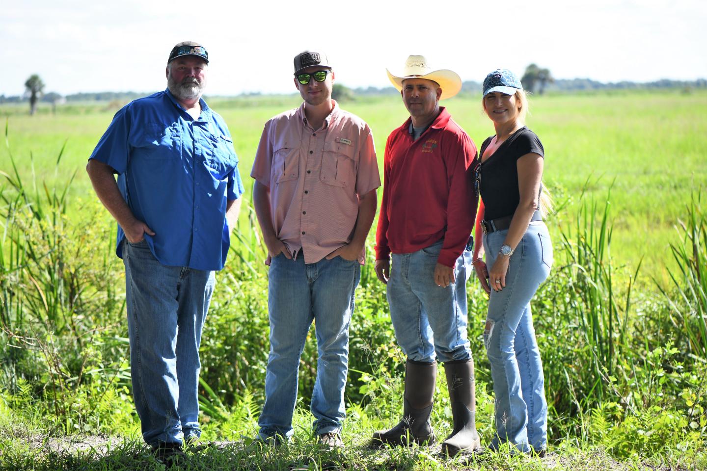 Four people stand in a sunny pasture field on a ranch in Florida.