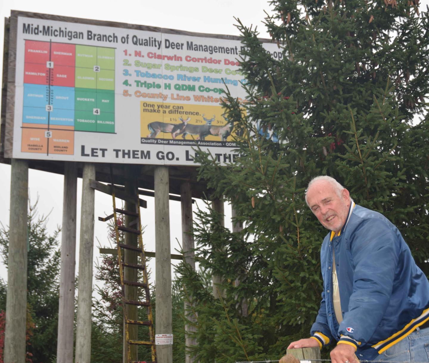 Charles Jones stands in front of Quality Deer Management sign on his property that also serves as a hunting blind.