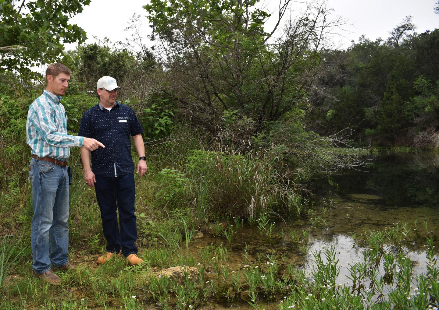 Two men stand outside a creek on Shield Ranch