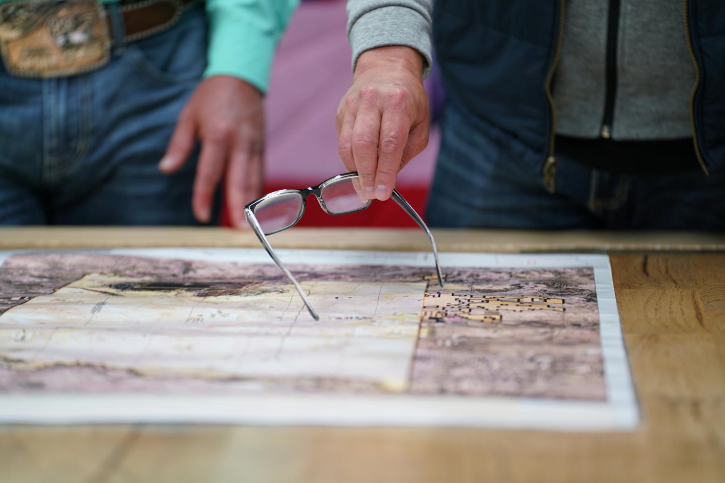 map on a table with someone pointing at it with glasses