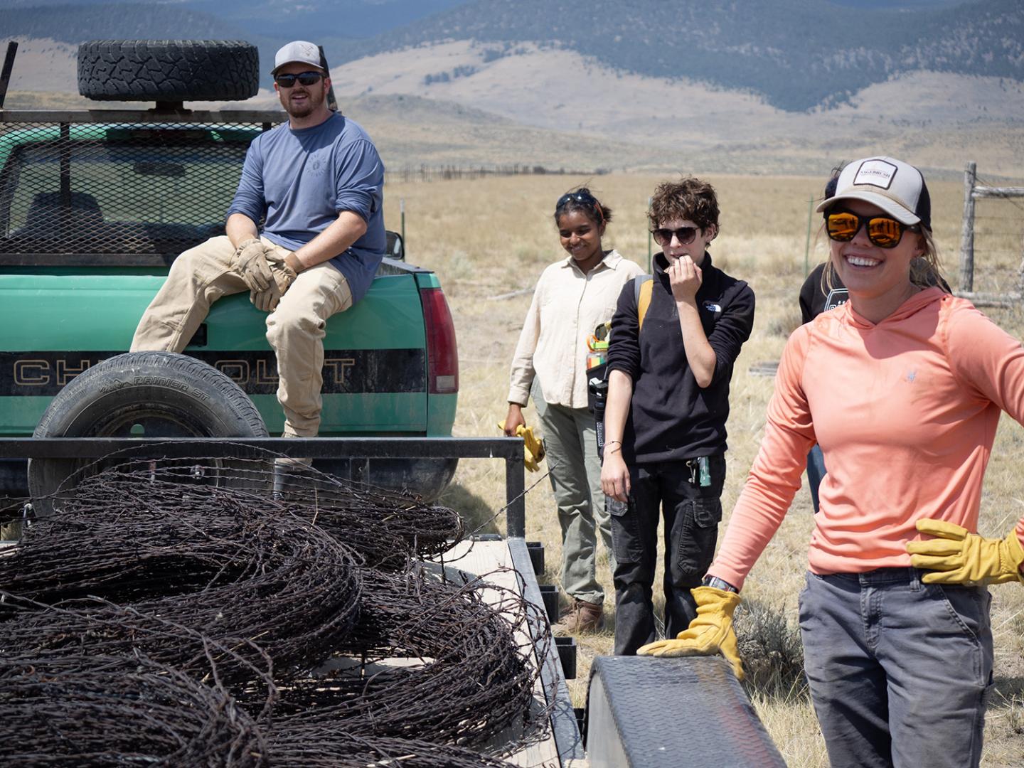 Youth stand around trailer full of old barbed wire removed from a derelict fence.