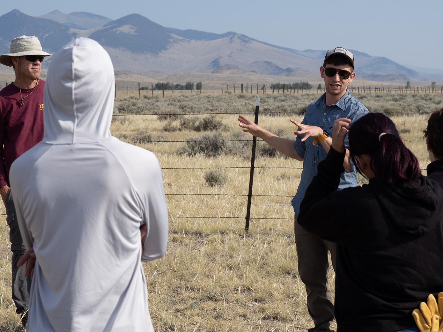 Man speaks to group of youth on the rangeland.