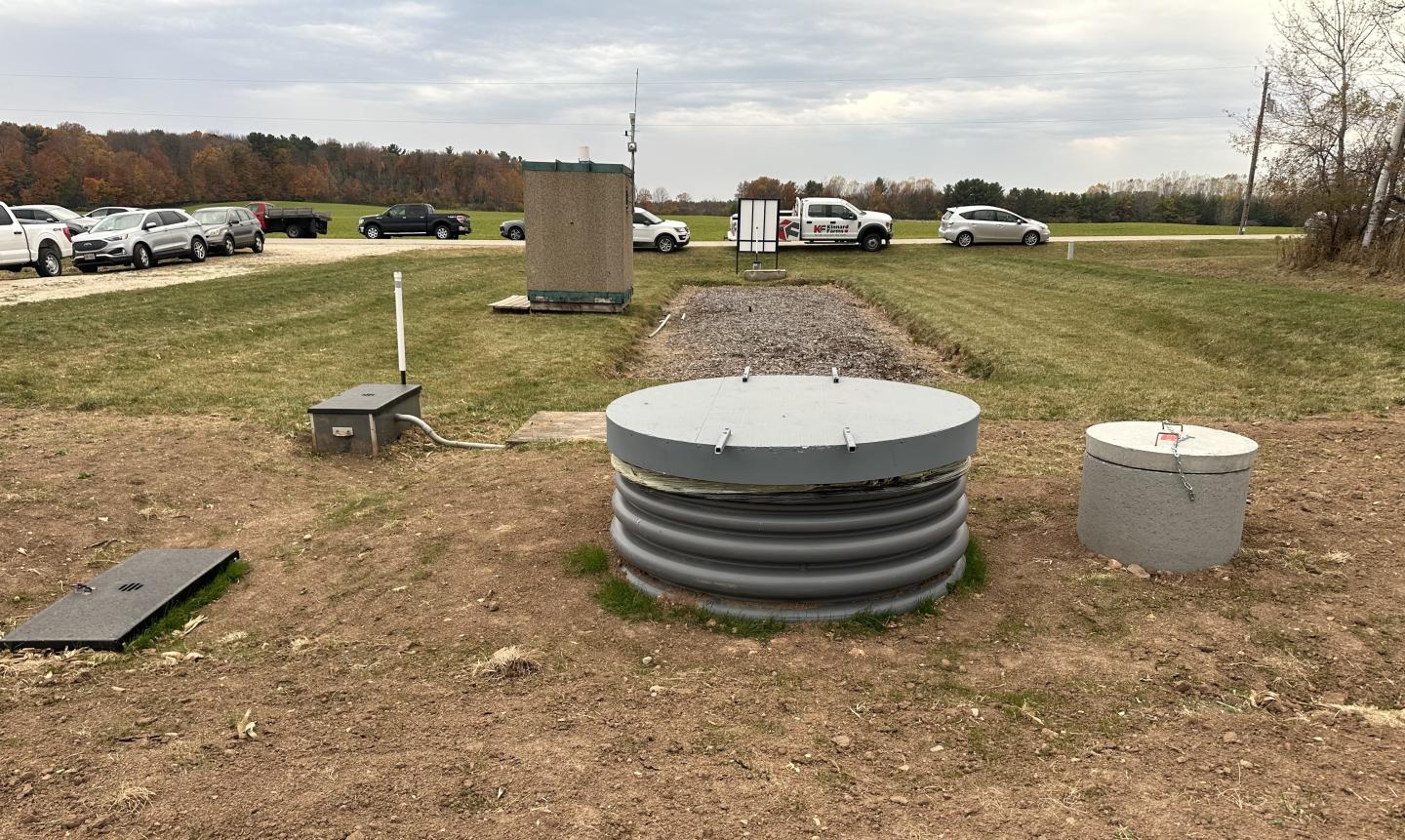 A view looking west of the Phosphorus Removal System and Denitrifying Bioreactor. Components include water control structures, HDPE access manhole to monitor flow, concrete holding tank riser, diversion embankment, woodchip bioreactor, and USGS monitoring controls structure.