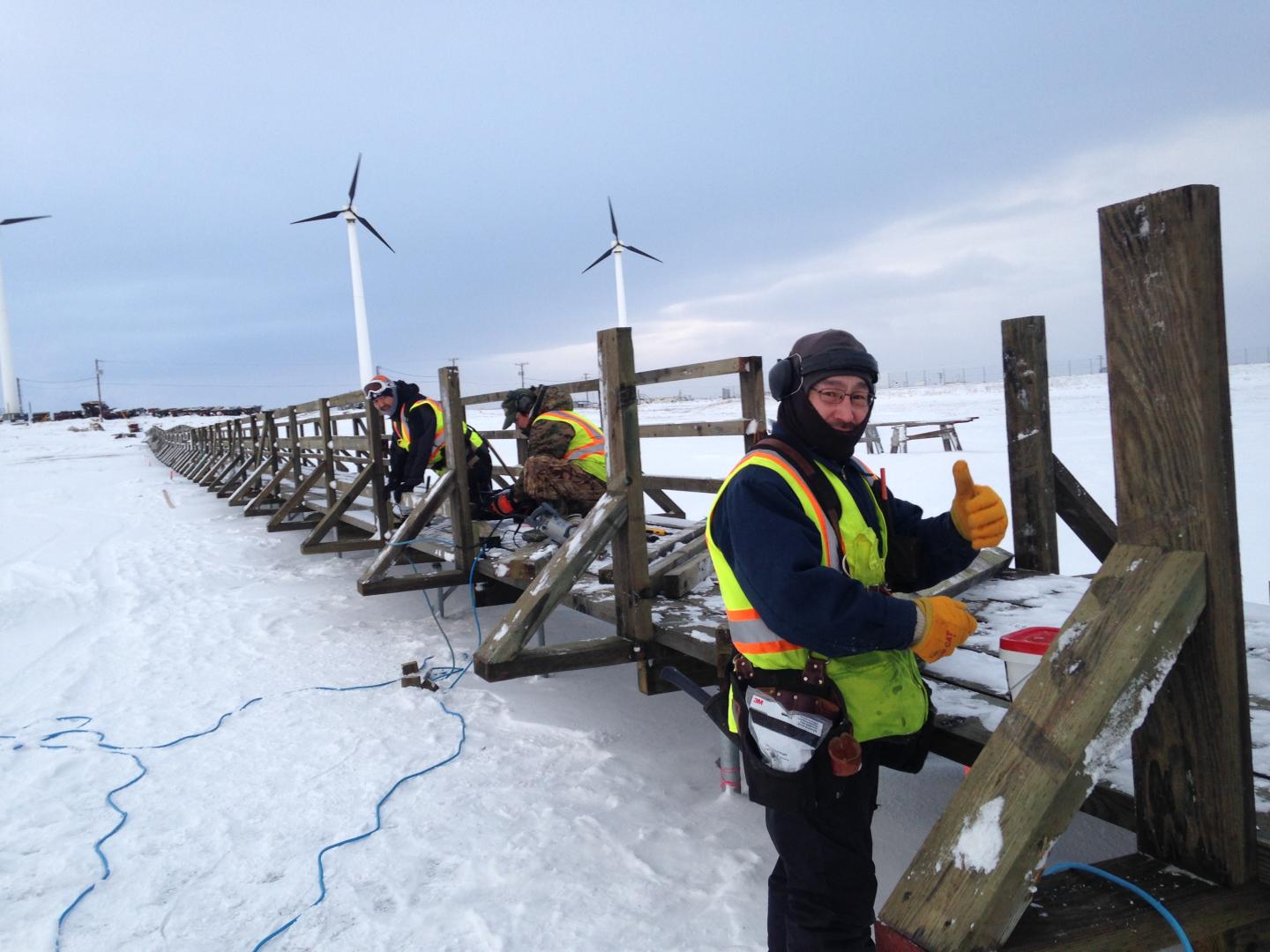 a man working on the Hooper Bay trail with windmills in the background