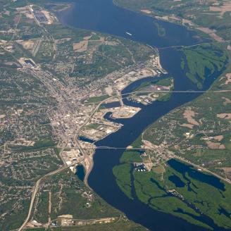 Aerial view of mixed land use in Iowa, including an urban area towards the center, forestland, and cropland. A river runs vertically through the image frame.