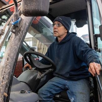 Guy Choiniere drives a tractor on his farm