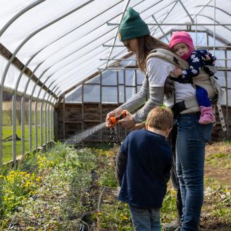 Savanna Crossman and her children water the plants inside a high tunnel on their farm.