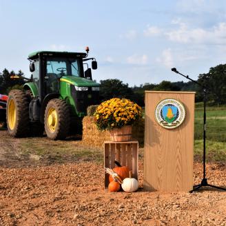 USDA podium in front of a tractor.