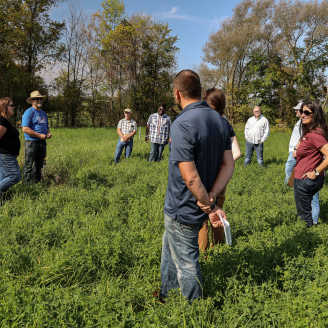 Group of people standing in a pasture.