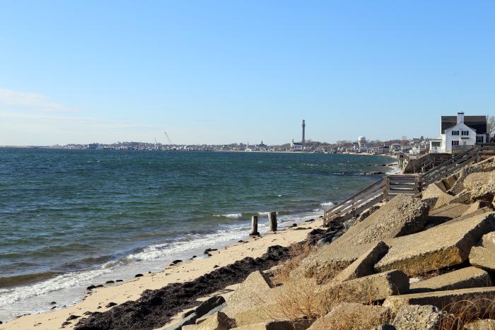 Provincetown Harbor and a seawall with Provincetown in the distance.