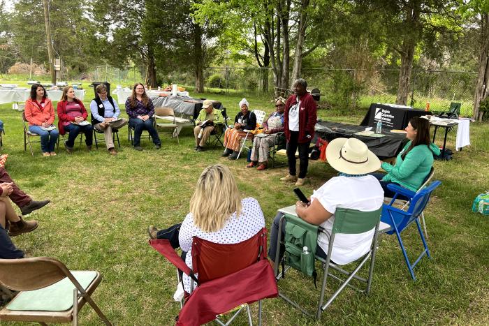 A group of people sitting outdoors at an outreach event hosted by Africulture.