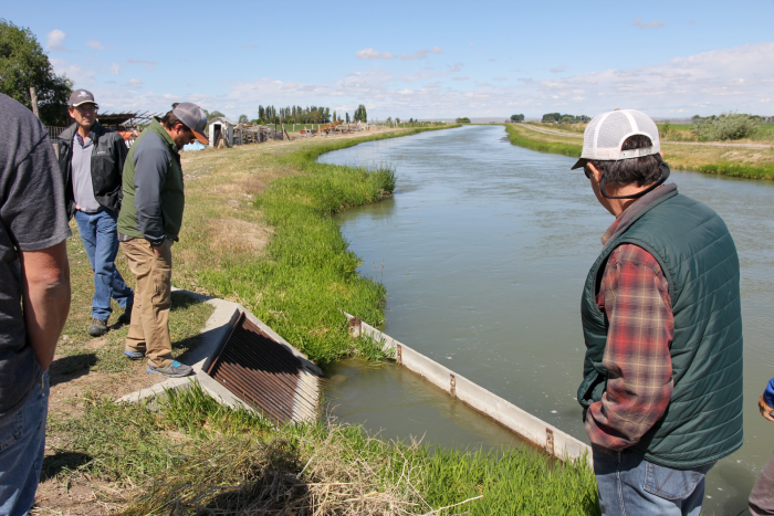 man explaining project to group of people by a canal