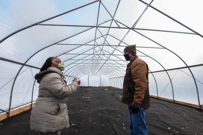 Aster Bekele, the founder of The Felege Hiywot Center in Indianapolis, Indiana, gives Jerod Chew, Indiana NRCS district conservationist, a tour of the center's high tunnel that was built in November 2020 and will be planted for the first time in Spring 2021. The high tunnel was funded in part through the NRCS's Environmental Quality Incentives Program. (Indiana NRCS photo by Brandon O'Connor)