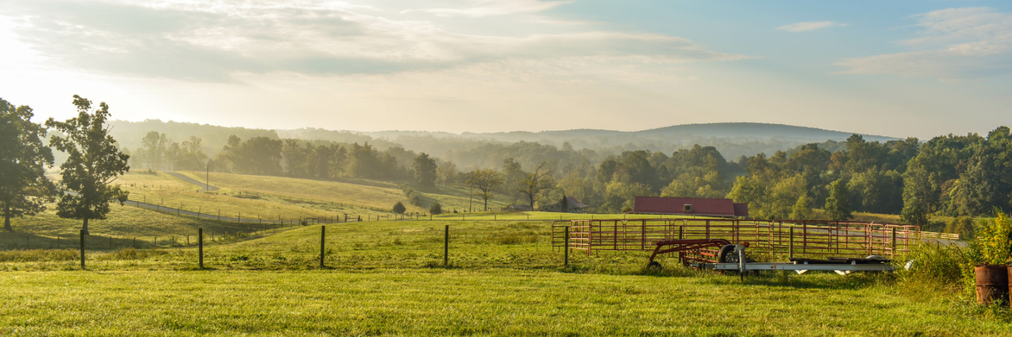 A beautiful farm with a fence in the foreground and a mountain range in the background