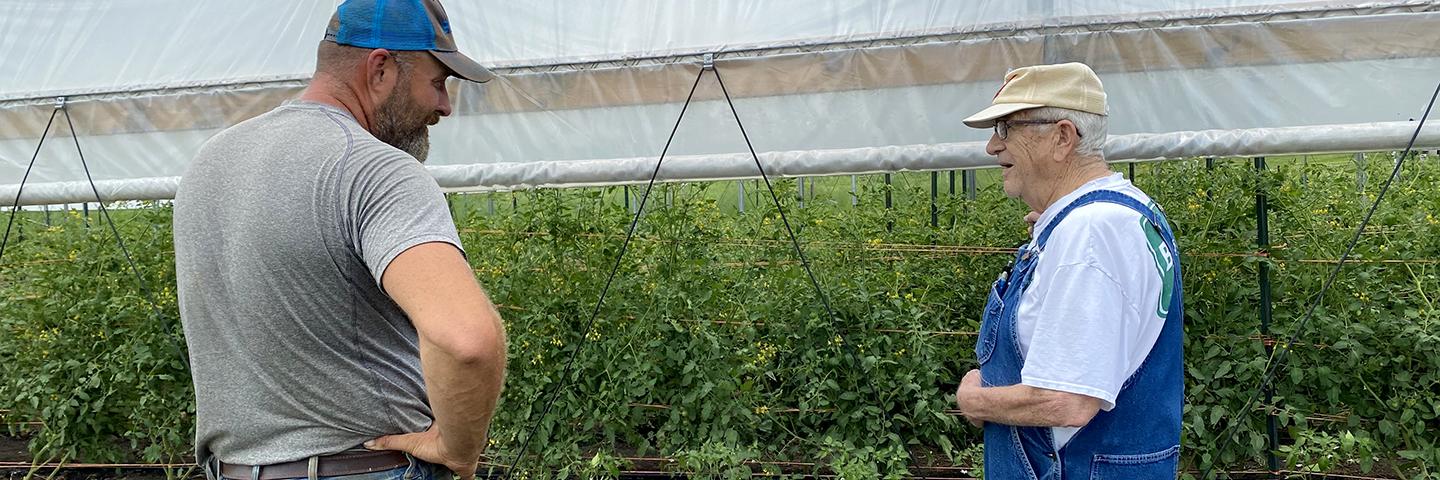 Charles Puffer helps a customer with produce by one of his high tunnels he installed with help from NRCS.