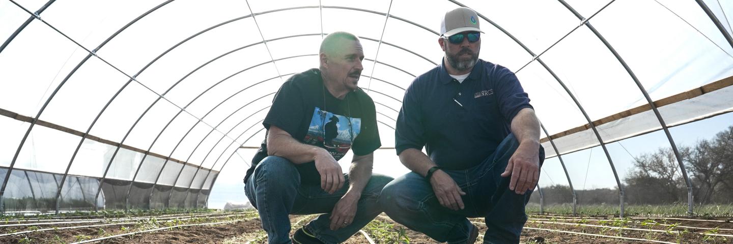 Texas NRCS employee visits with the owner of the Texas Food Ranch inside a high tunnel/