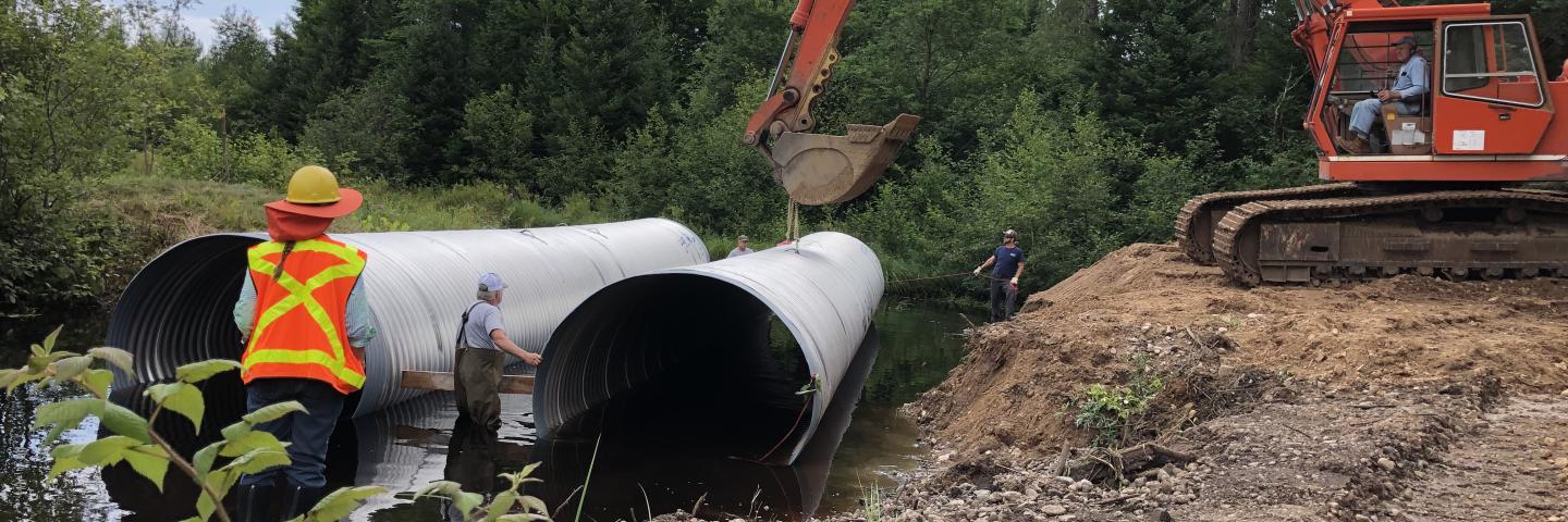 Pictured are the two 87” x 63” x 50’ aluminized steel arched culverts being placed in the stream bed. 
