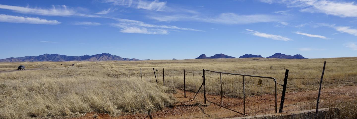 Arizona Rangeland with livestock fence and gate on a dirt road near a highway
