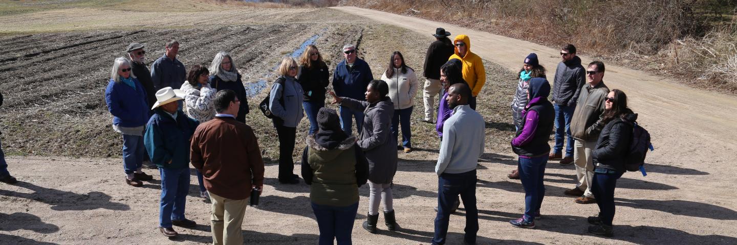 A group of people outdoors discussing a conservation project.