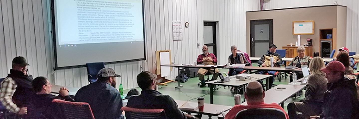 A group of people sitting around tables looking at a presentation.