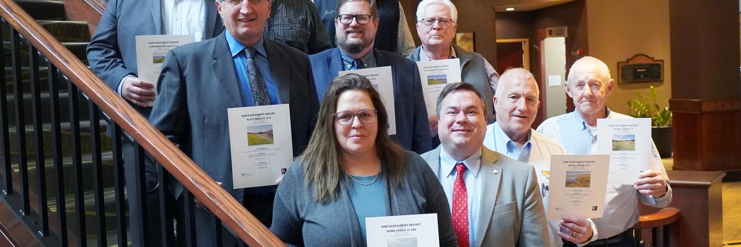 A group standing on a stairwell holding certificates. 