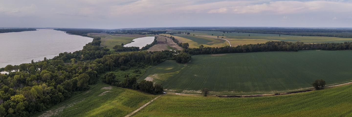 Overhead shot of a river with green fields on its right