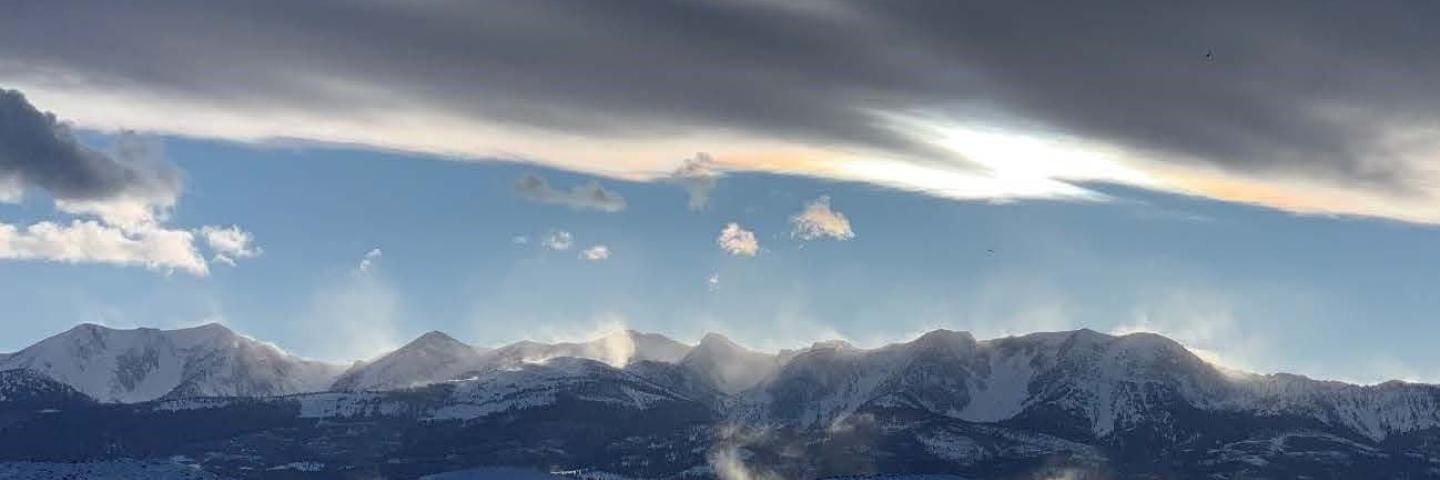 Snowy mountain range with clouds covering the sun