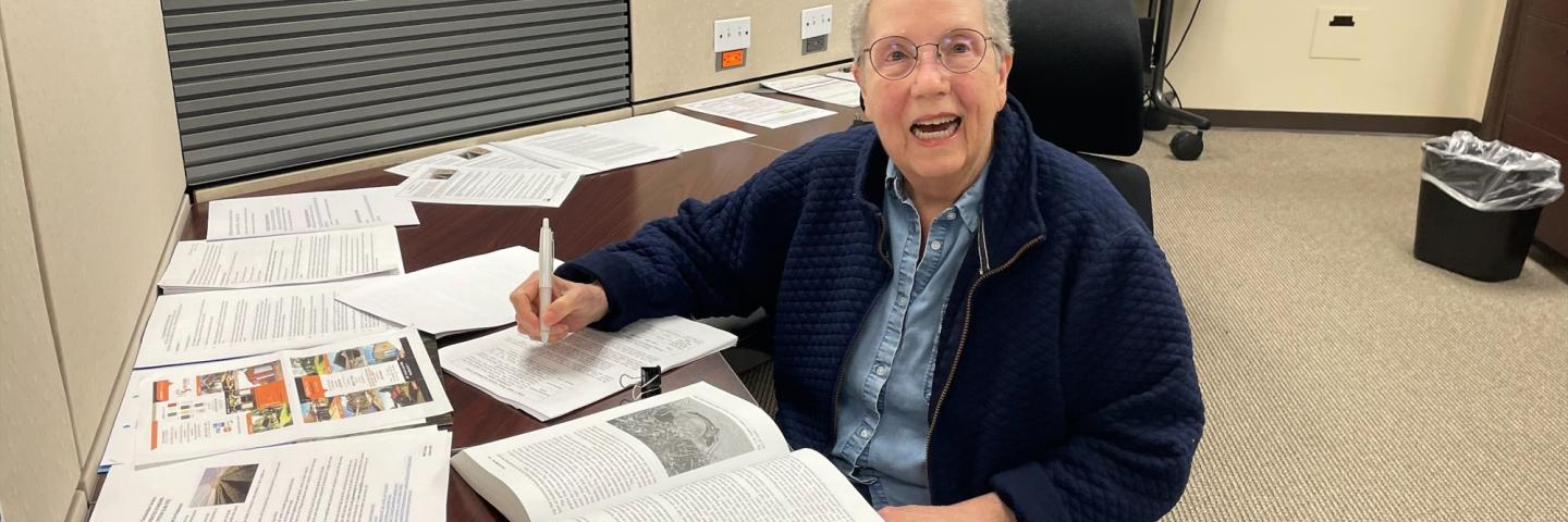 Earth Team Volunteer Linda Johnson seated at a desk in the office she's volunteered at for 30-plus years.