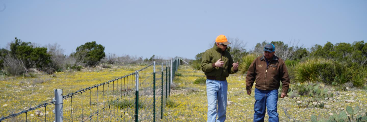 (L-R) 7 Oaks Ranch owner Wayne Walker and NRCS Eldorado resource team leader Alfredo Munoz walk along a recently installed fence. The fence and its placement were part of a comprehensive conservation plan for the ranch. This was planned and made financially feasible through assistance from the NRCS.