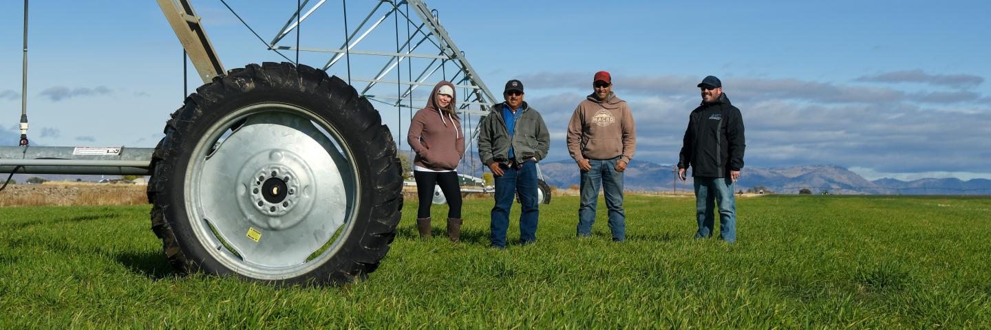 Jenn Eatwell, Fidel Garcia, Jamie Cruz, and Lars Santana standing in field near pivot irrigation system