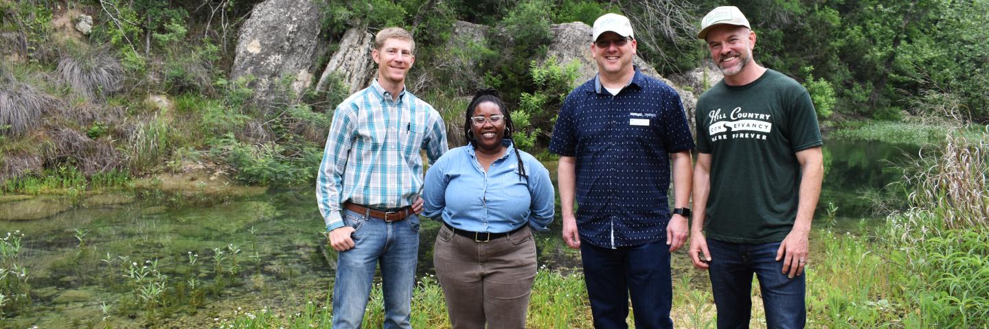 three men and two women stand outside of a creek