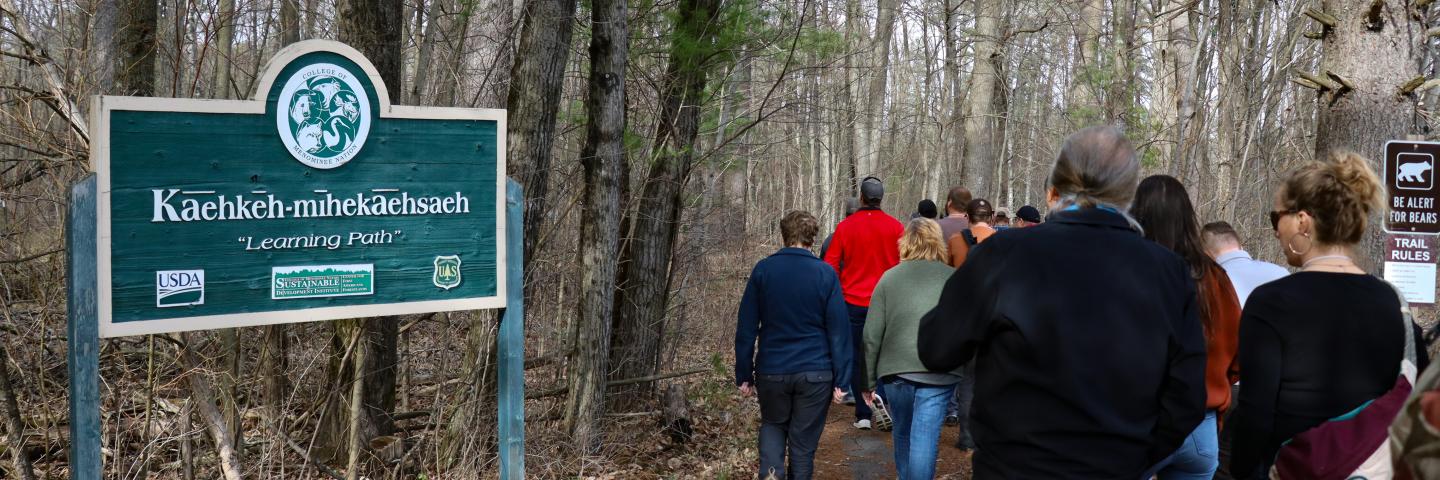 A trail sign leading into the woods.