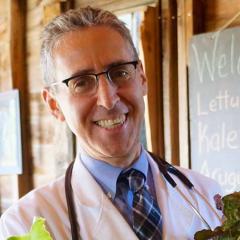 Dr. Ron Weiss smiles and holds up produce.