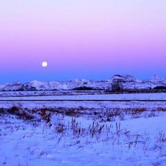 Moon over snow-covered fields and badlands, Prairie County, Montana