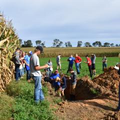 FFA Students evaluating a soil pit dug next to a corn field for a land evaluation competition 