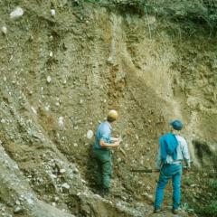 Two men observing slope of soil erosion 