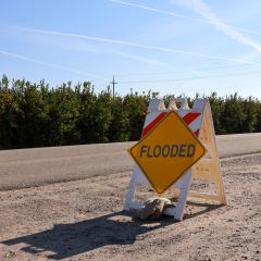 Orange warning flooded sign-dusty road in Fresno, CA