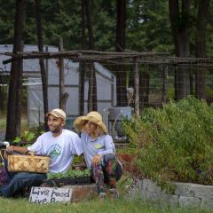 Male and female urban and small farmers with crops and hoop house in the background