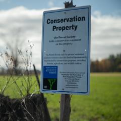 A sign indicating the boundary of a conservation Easement stands in a field in New Hampshire. 