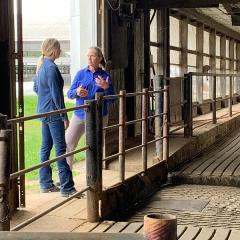 Iowa NRCS District Conservationist LuAnn Rolling (right) speaks with dairy operator Ann Deering about her new dairy barn energy efficient lighting system.