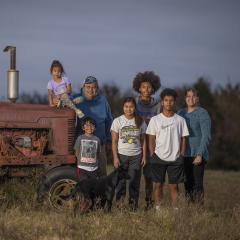 A family standing next to a tractor in a field.