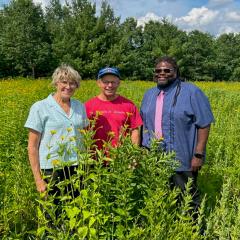 Three people standing in a prairie planting.