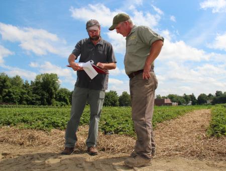 NRCS planner and farmer looking at a conservation plan in the field.