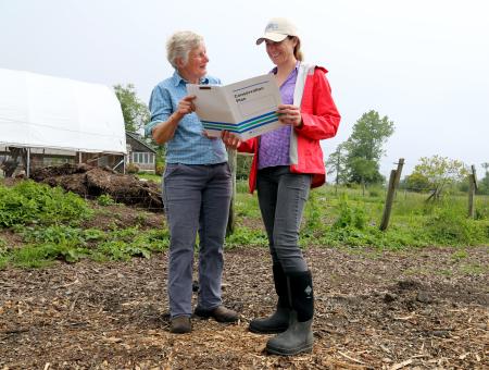 A farmer and an NRCS planner look at a conservation plan in the field.