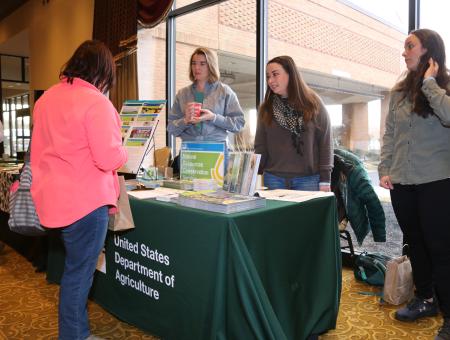 NRCS employees staffing a table at an outreach event.
